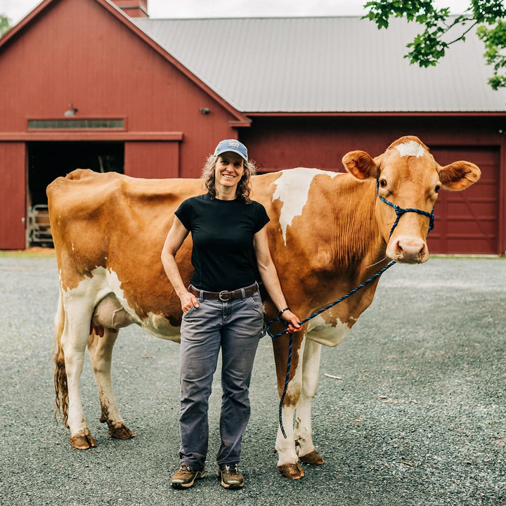 Woman wearing Merino crew stands with prize dairy cow 