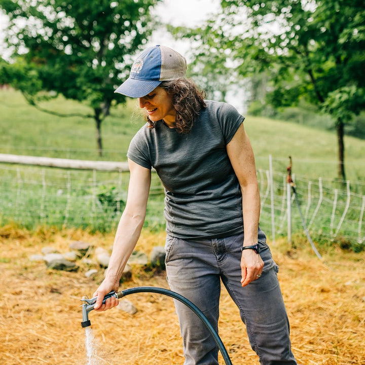 Woman wearing merino wool short sleeve shirt fills water bucket 