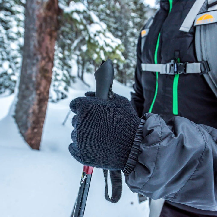 Hiker holds a trekking pole in lightweight merino glove liners 