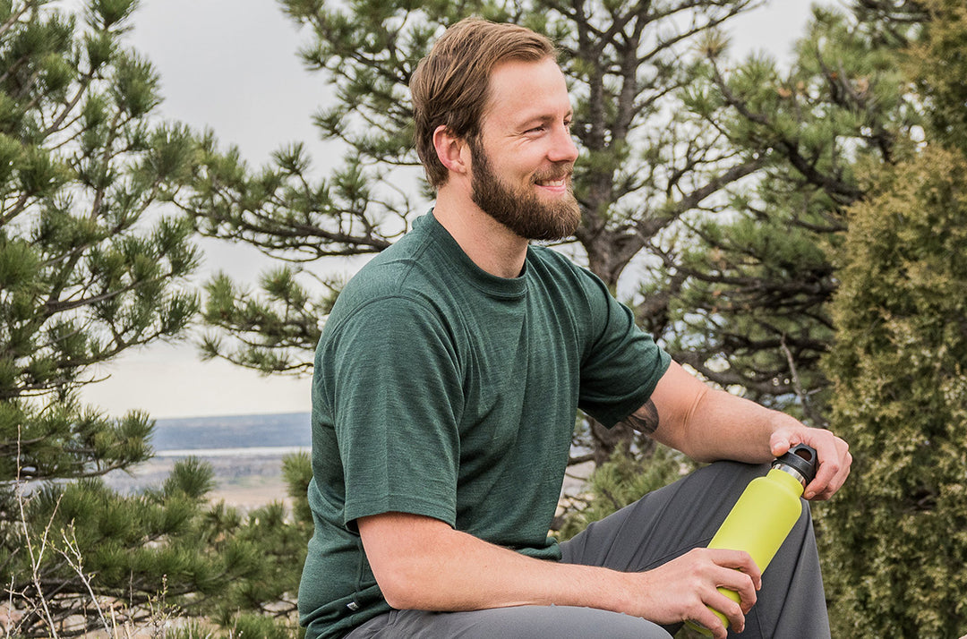 man sitting on rock wearing merino wool lightweight t-shirt