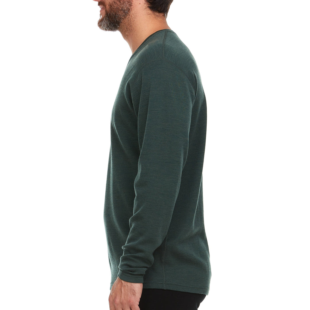 Left-facing side view of a man wearing a forest green midweight merino wool long-sleeve V-neck sweater, showing the shoulder seam, close-fitting sleeve, narrow cuff, and slightly curved hem 