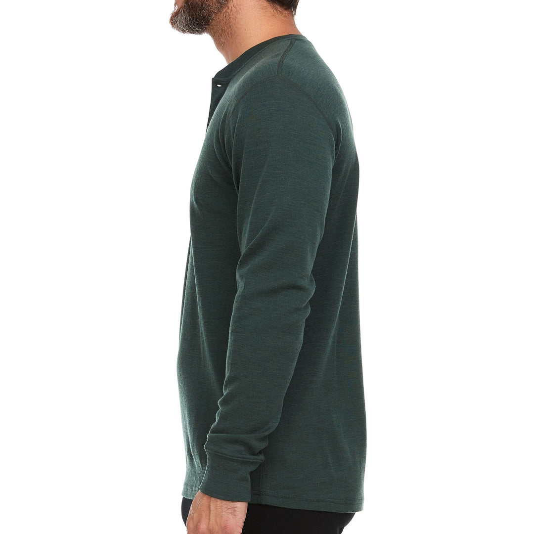 Right side view of a man wearing a forest green midweight merino wool long-sleeve henley shirt, showing the shoulder seam, fitted sleeve and cuff, and straight hip-length hem 