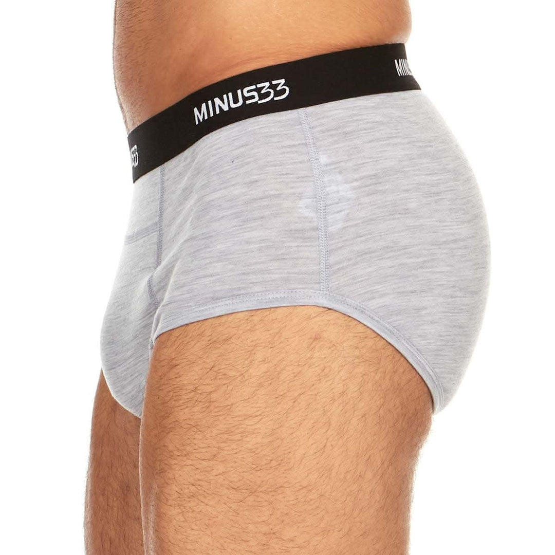 Left side view from waist to upper thighs of a man wearing ash gray Woolverino micro weight merino wool briefs, showing the elastic waistband, smooth side panel, high-cut leg opening, and close fit 
