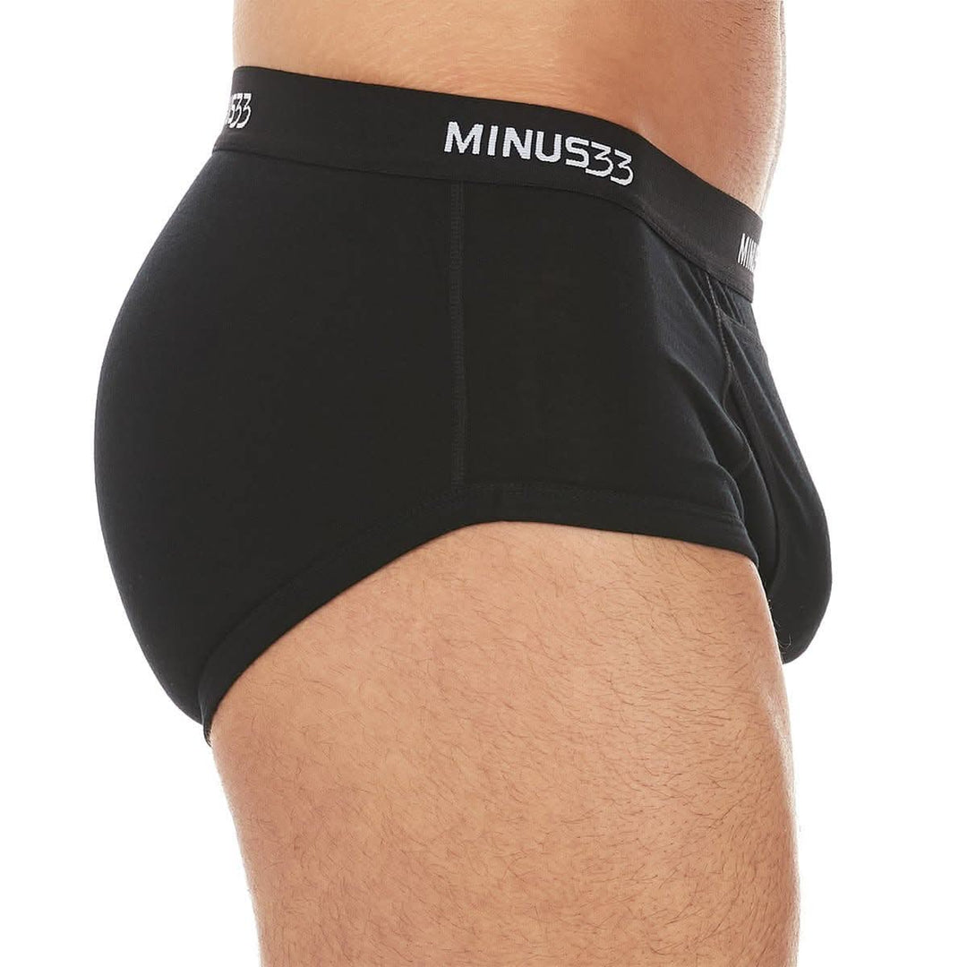 Right side close-up from waist to upper thighs of a man wearing black Woolverino micro weight merino wool briefs, showing the elastic waistband, smooth side panel, high-cut leg opening, and close fit 
