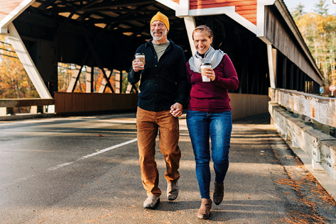 couple on wooden covered bridge wearing merino wool scarf merino wool beanie and merino wool base layers