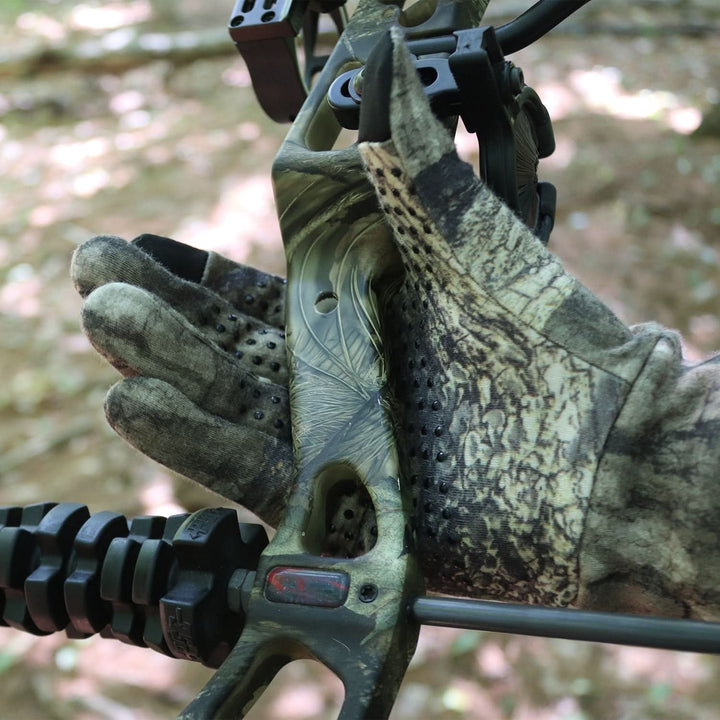 Man in Mossy Oak Merino touchscreen gloves with grip dots holding hunting bow 