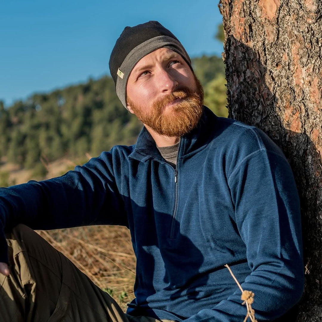 A man models the merino wool midweight quarter zip sweater, complete with flat-lock seams and thumbholes, close-up of the product left-facing side view 