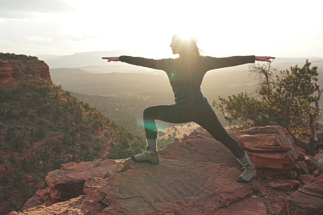 woman doing yoga on top of a mountain in merino wool base layers