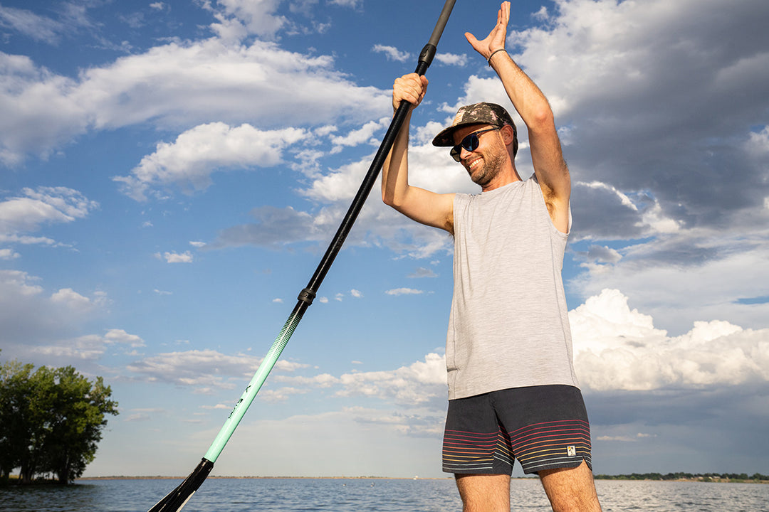 man paddle boarding with sleevless tank 